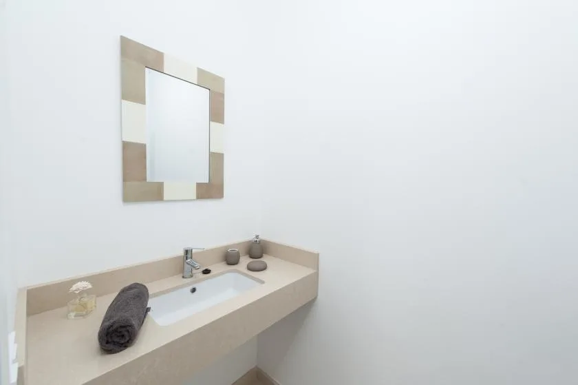 A bathroom vanity with a sink, faucet, and wall mirror.