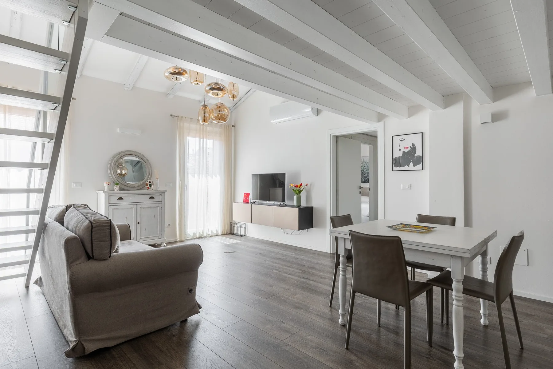 A bright open-plan living and dining room with a gray sofa and dining table.