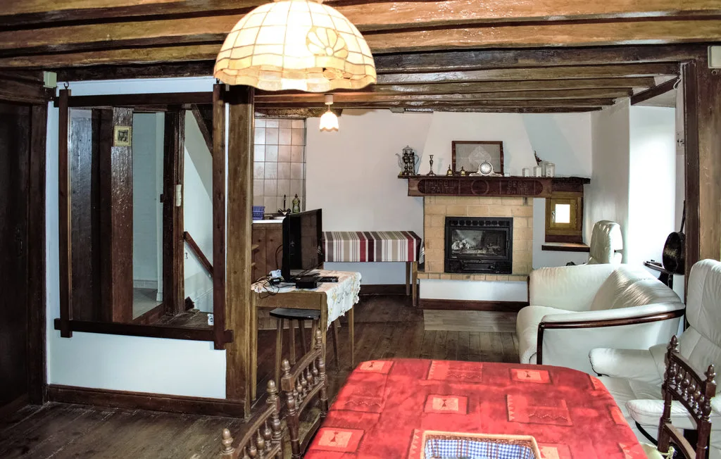 A rustic living room with a fireplace, seating, and exposed wooden beams.