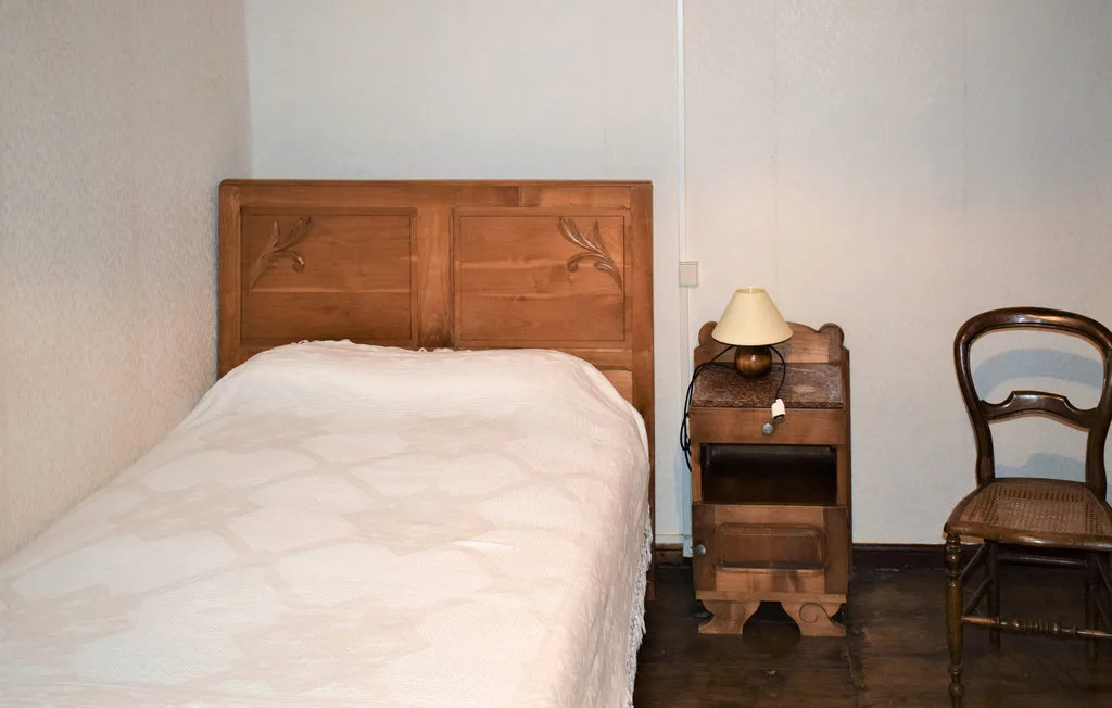 A bedroom with a wooden bed, bedside table, and chair.