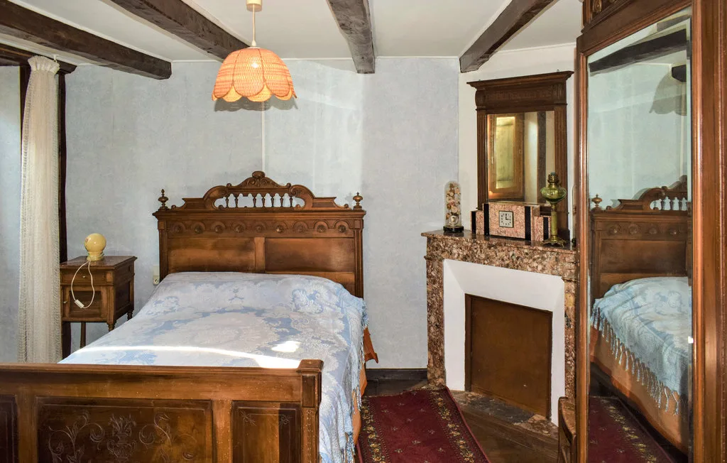 A bedroom with a wooden bed, a fireplace, and a large mirror.