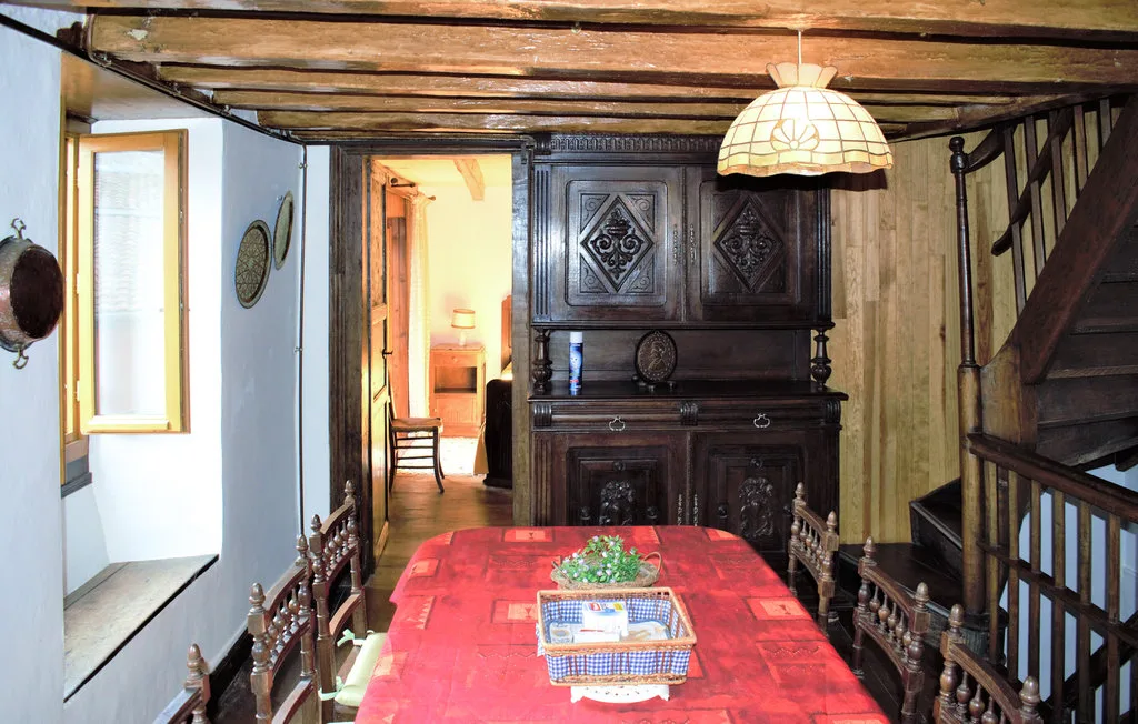 A rustic dining room with a red-covered table beneath a timber ceiling.