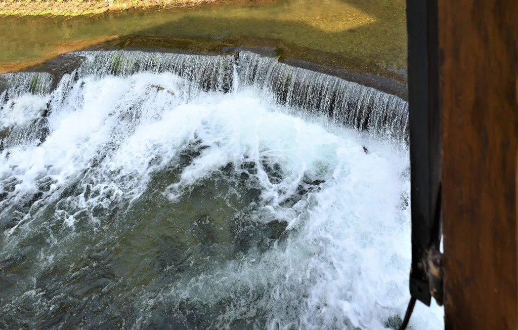 A small waterfall pours over a low ledge into churning water.