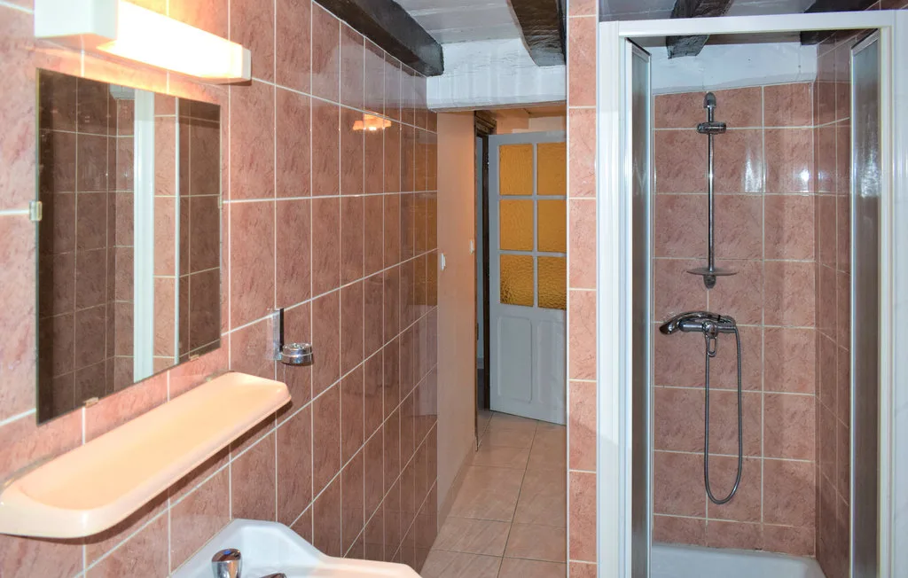A tiled bathroom with a sink, mirror, and shower.