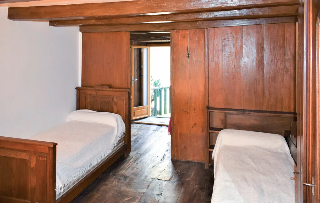 A wood-paneled bedroom with two beds and an open doorway.
