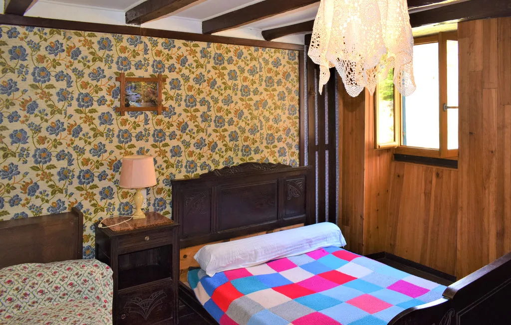 A bedroom with a bed covered by a colorful checked blanket.
