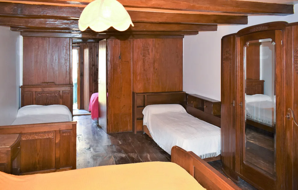 A bedroom with several beds, wooden furniture, and exposed ceiling beams.