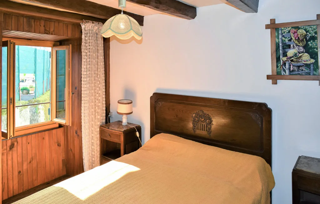 A bedroom with a wooden bed beside an open window.