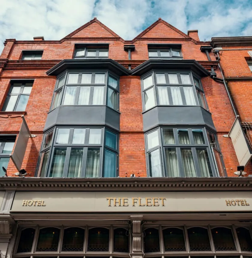 Red-brick hotel facade with bay windows.