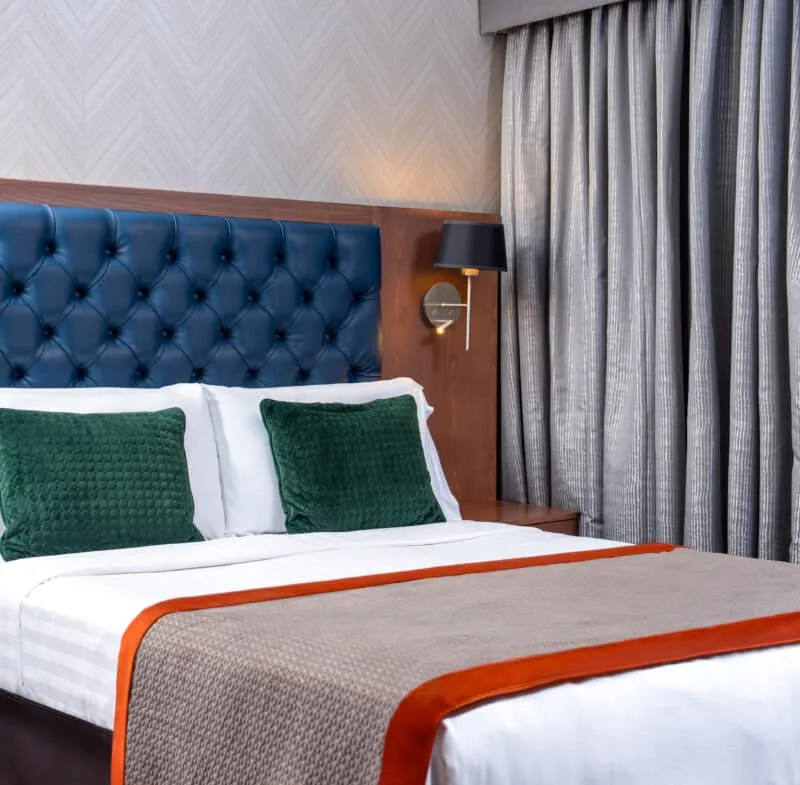 Hotel room with duvet, cushions and ambient lighting.