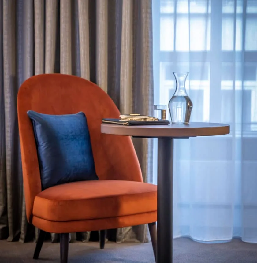 Hotel room sitting area with an orange chair and blue cushion.