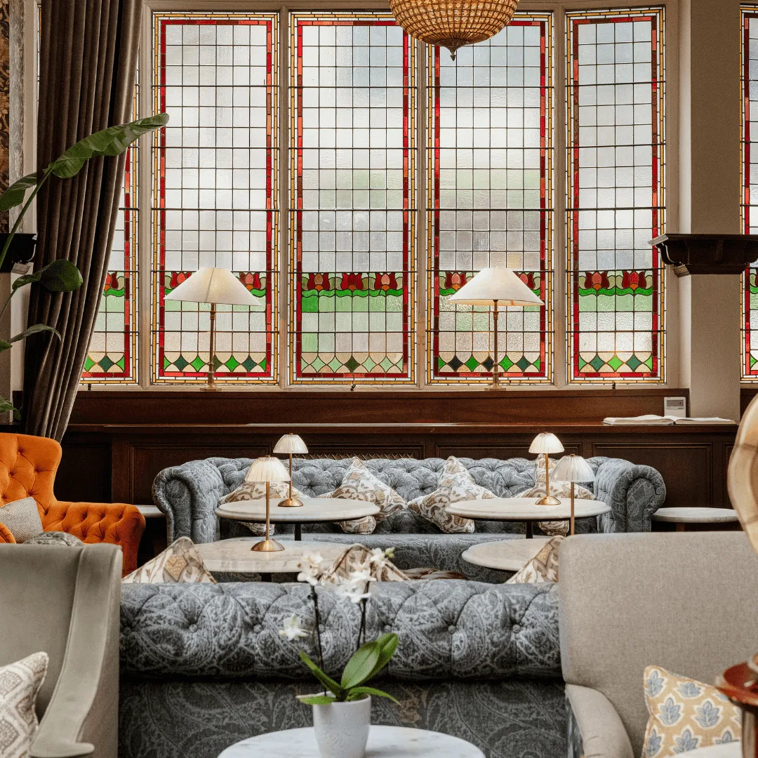 Hotel lounge with plush seating and stained-glass windows.