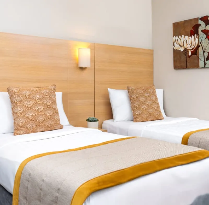Hotel room with twin beds and floral artwork.