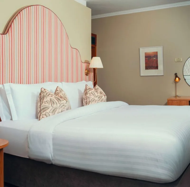 Hotel room with a king-size bed and desk area.