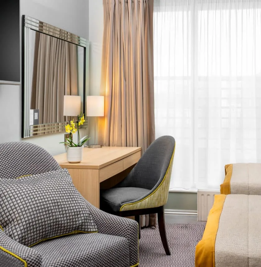 Hotel room with twin beds, desk and flat-screen TV.