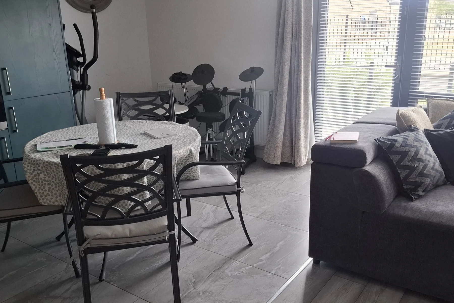 Zona de estar y comedor con una mesa, asientos y una batería electrónica.