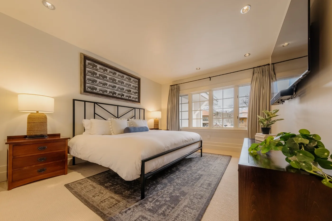 A bedroom with a bed, bedside table, and large windows.