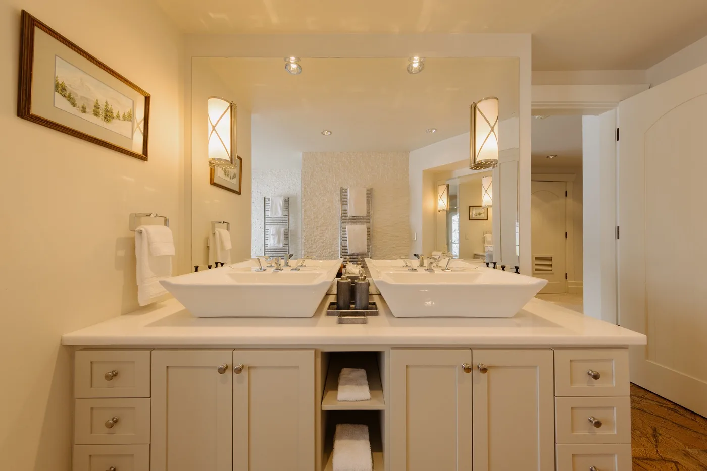 A bathroom vanity with two sinks, mirrors, and wall-mounted lights.