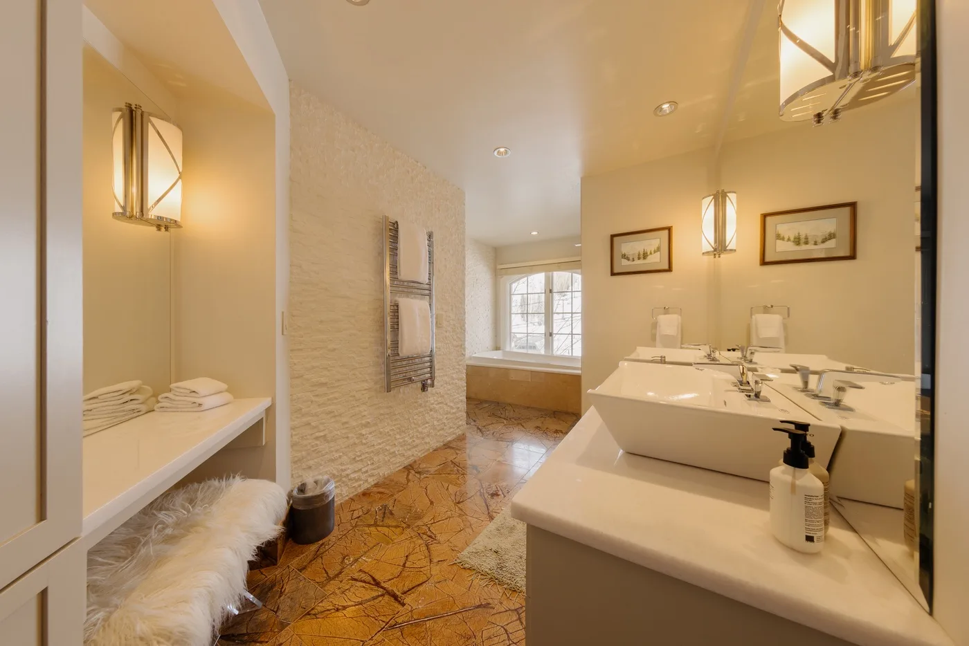 A spacious bathroom with a double vanity, bathtub, and window.