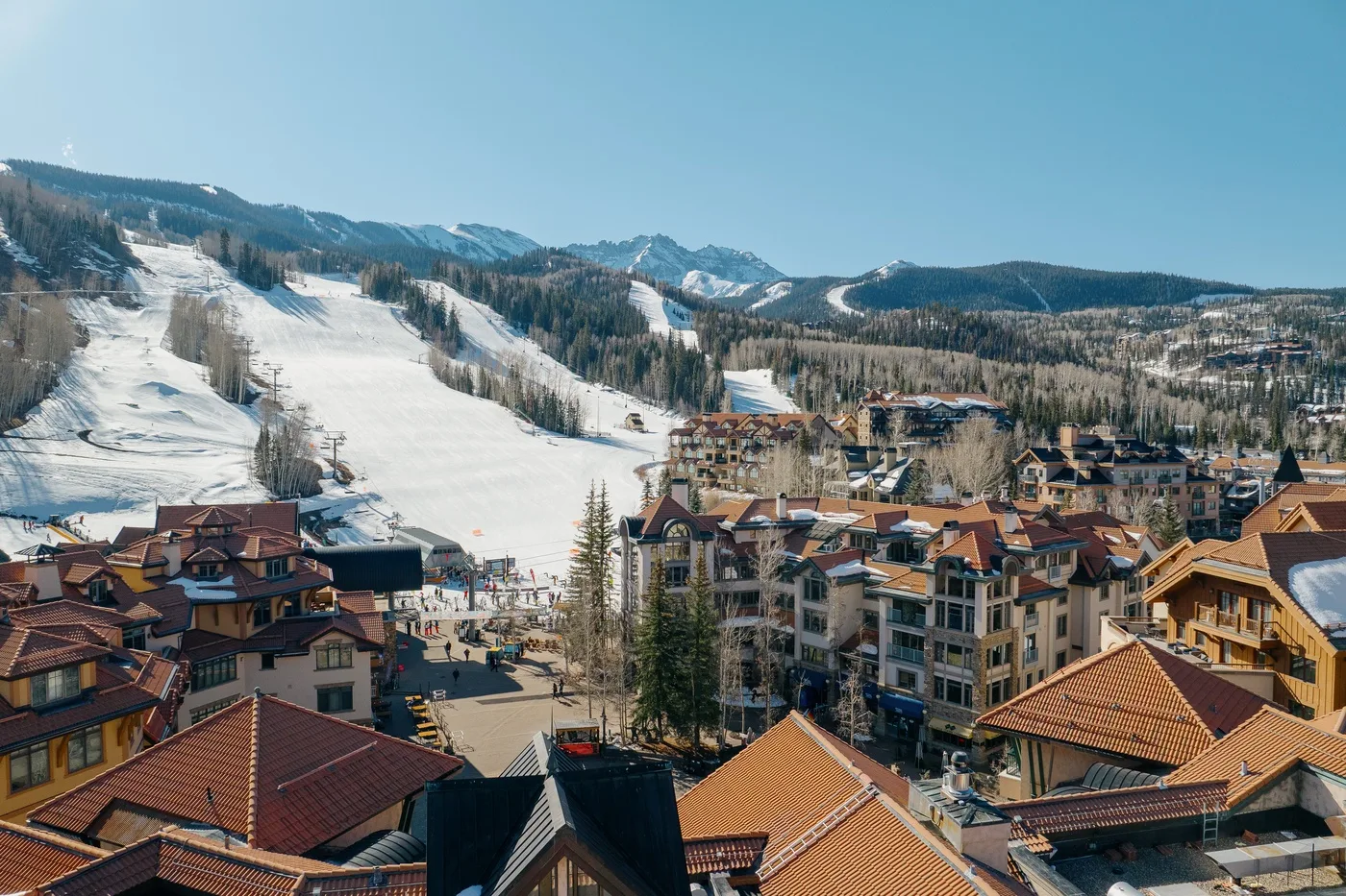 A mountain ski resort with snow-covered slopes and buildings with red roofs.