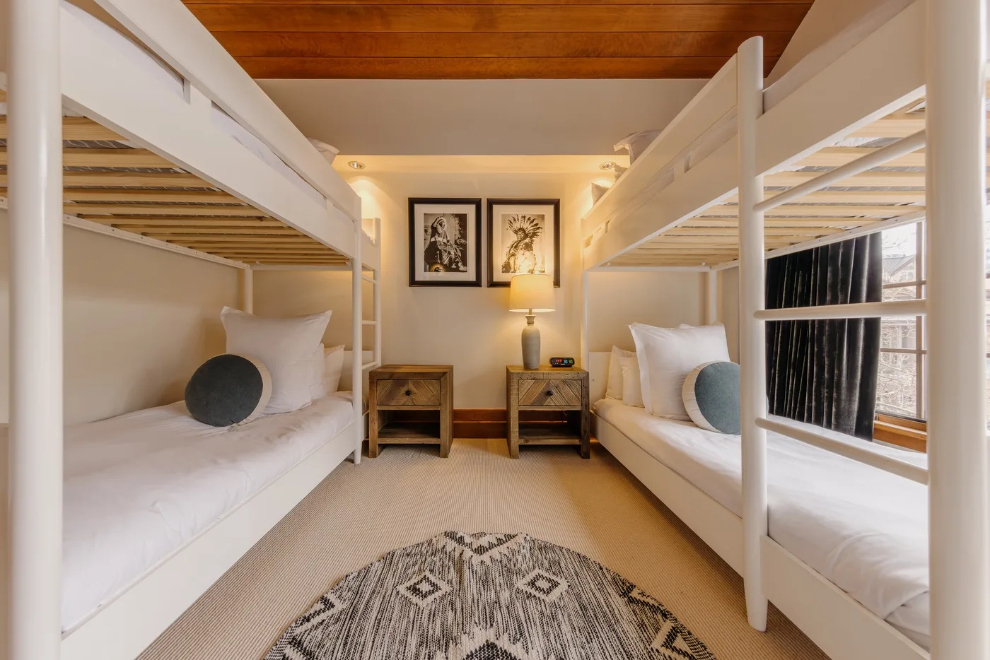 A bunk bedroom with two white beds and framed artwork on the wall.