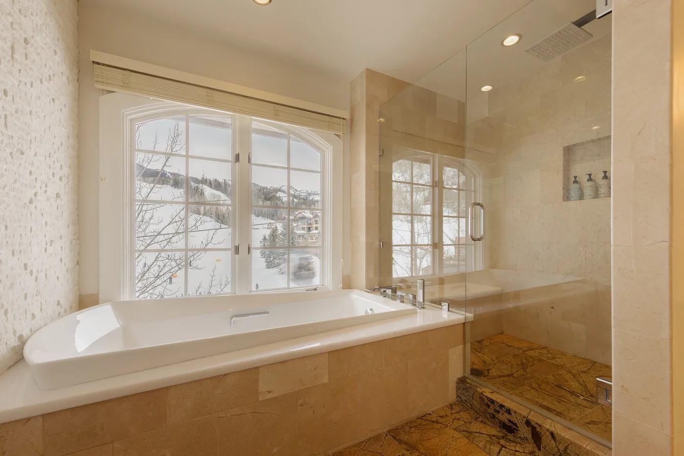 A bathroom with a built-in bathtub beside a glass-enclosed shower.