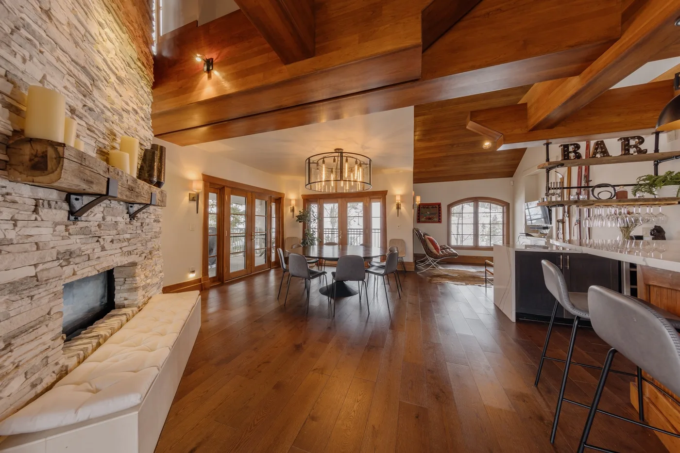 A spacious living and dining area features a stone fireplace and wooden beams.