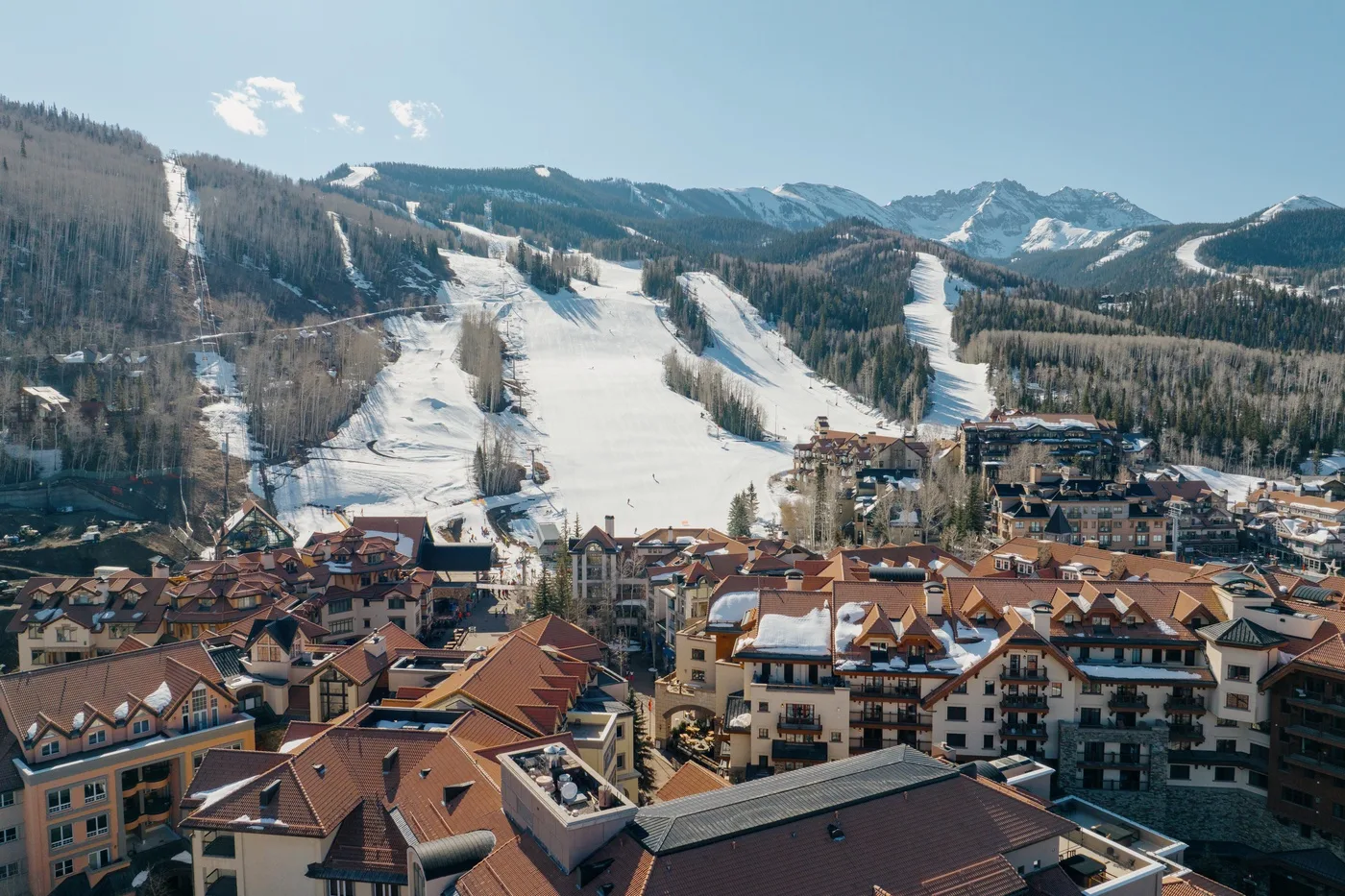 Mountain ski slopes rise behind a cluster of resort buildings.