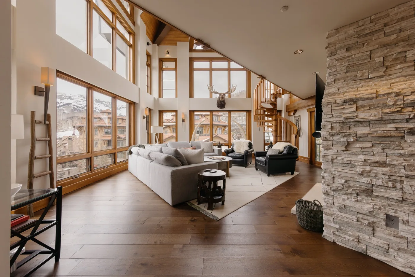 A spacious living room with seating beside tall windows and a stone fireplace.