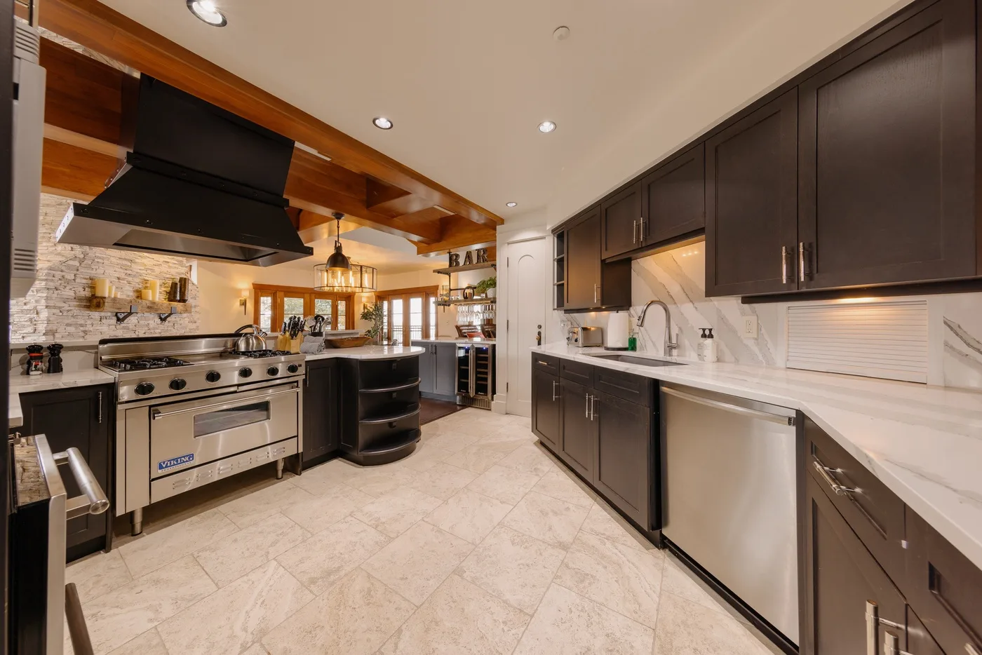 A spacious kitchen with dark cabinetry, a large range, and light stone countertops.