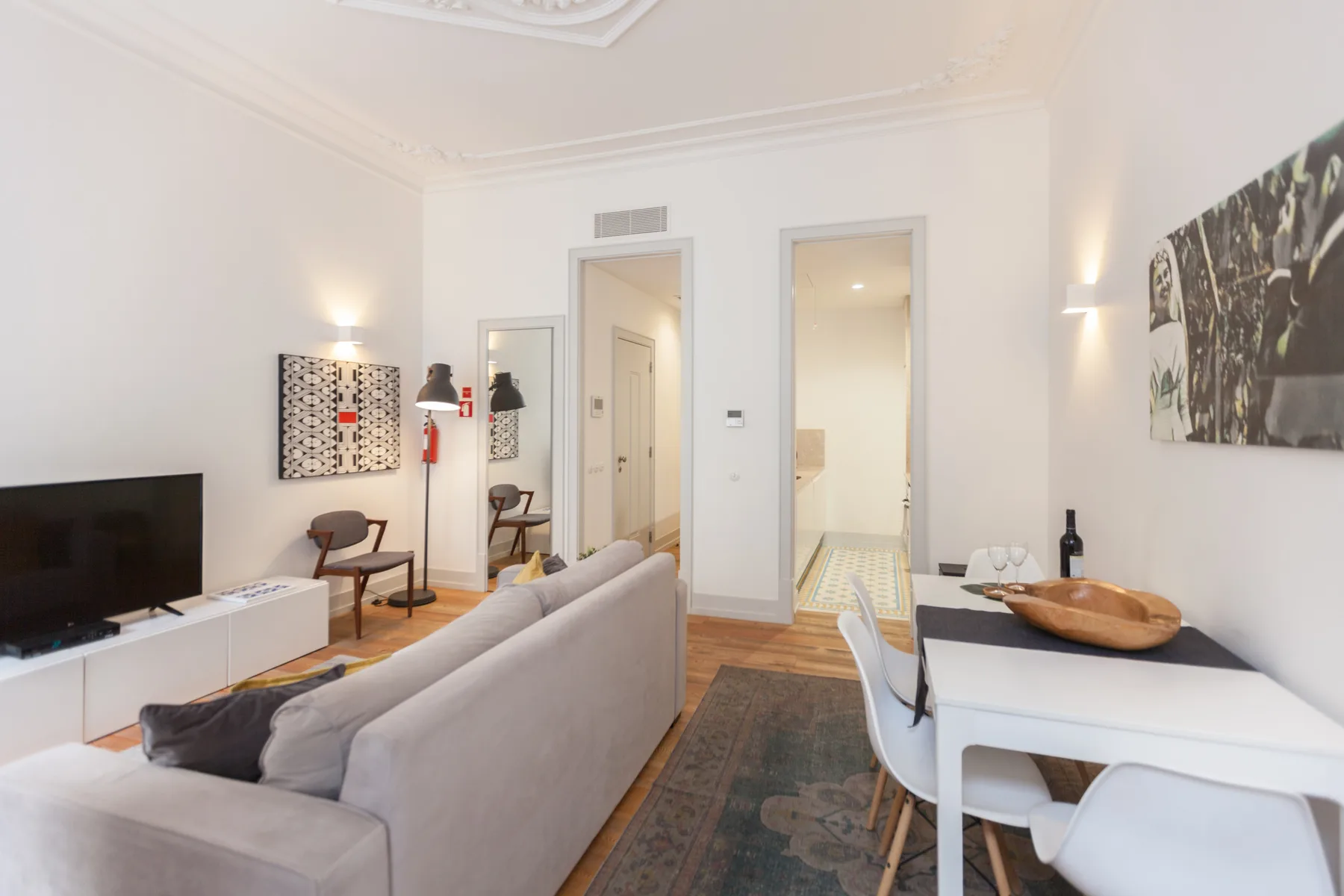 Un salón luminoso con asientos, un televisor y una mesa de comedor.
