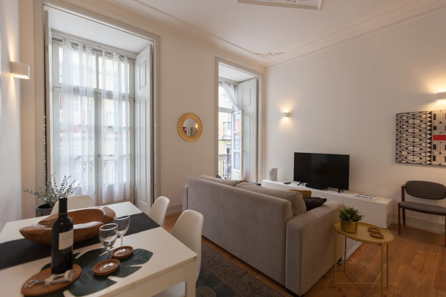 Una luminosa sala de estar y comedor con grandes ventanas y asientos.
