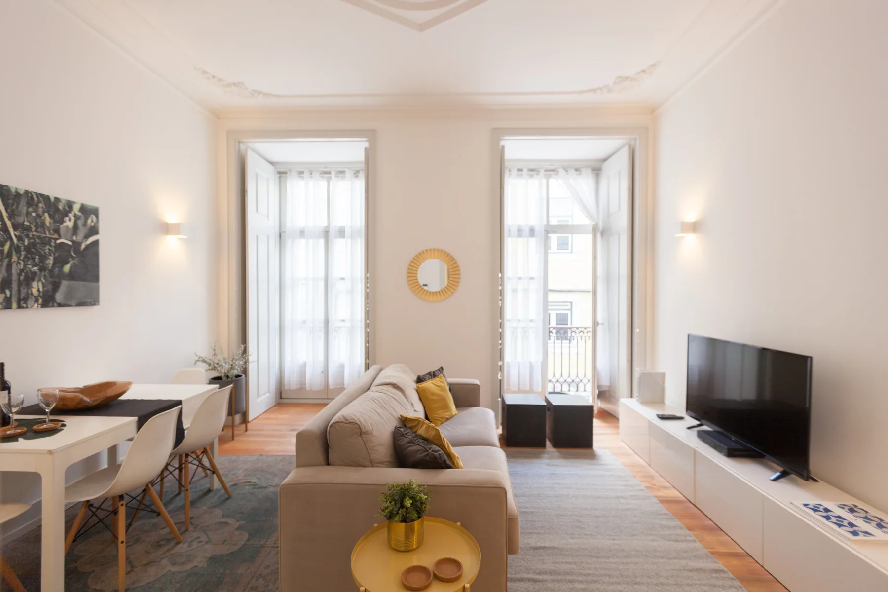 Una sala luminosa con asientos, un televisor y ventanas altas.
