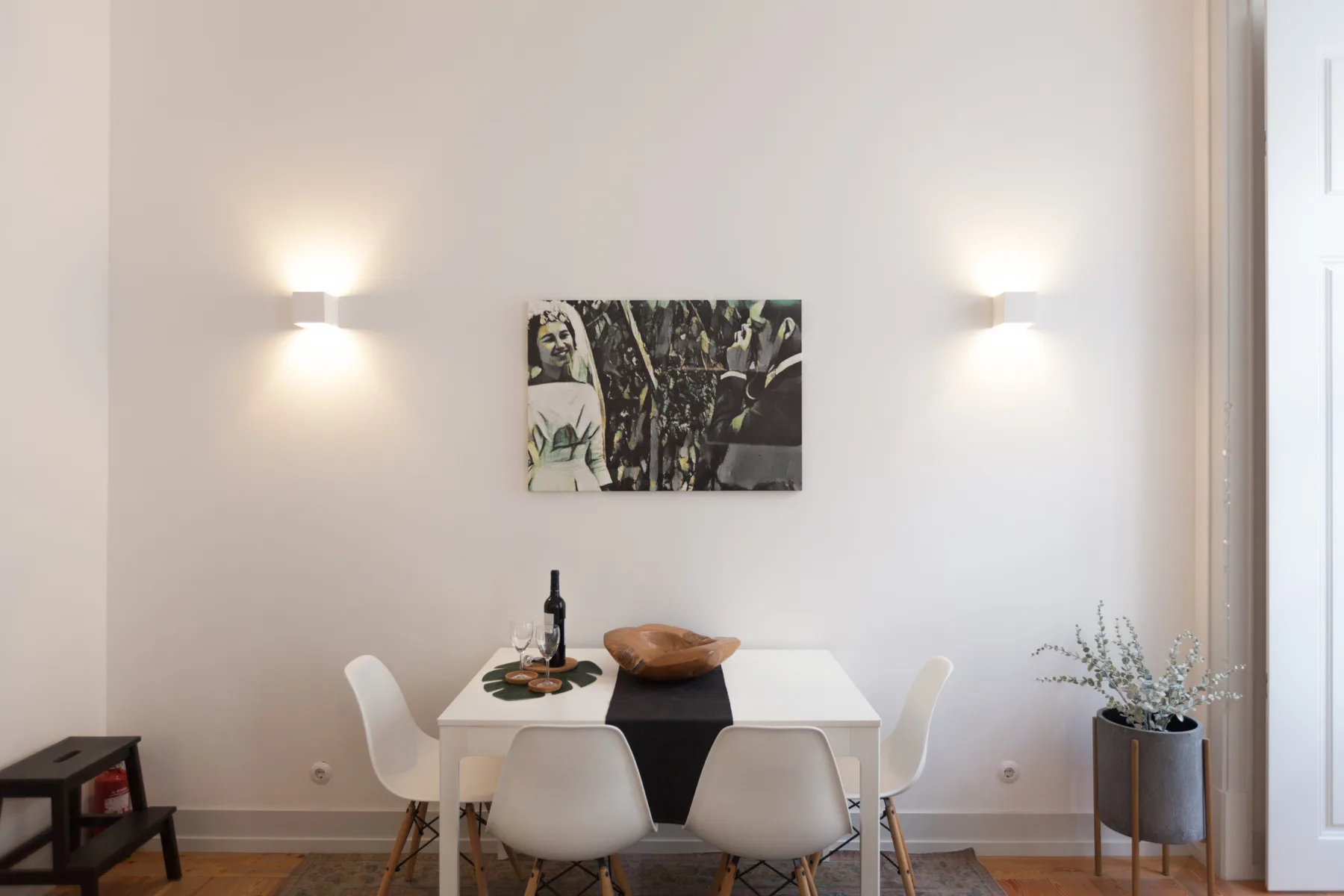 Comedor con una mesa blanca, sillas y un cuadro en la pared.