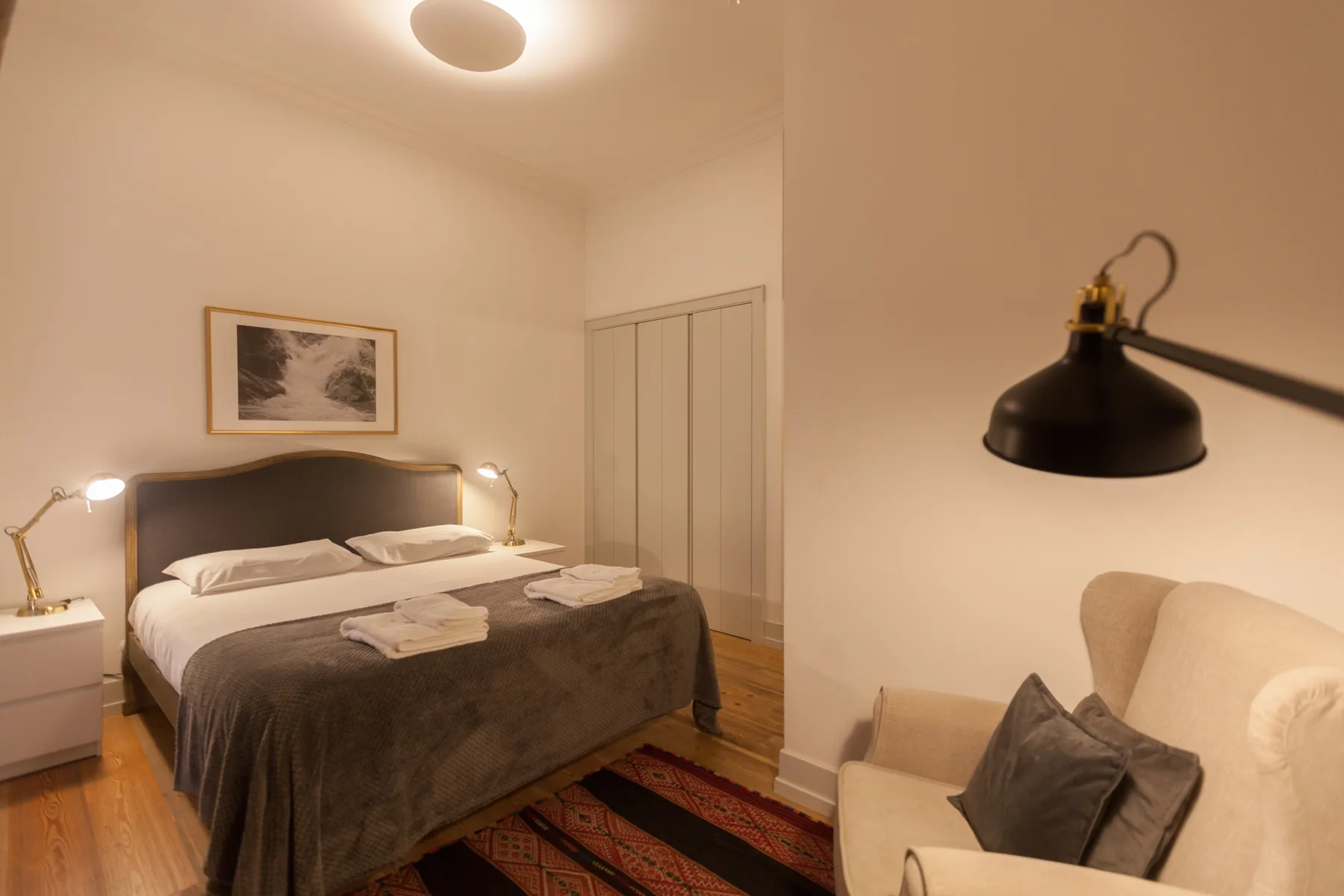 Un dormitorio con una cama tendida y una zona de estar al lado.