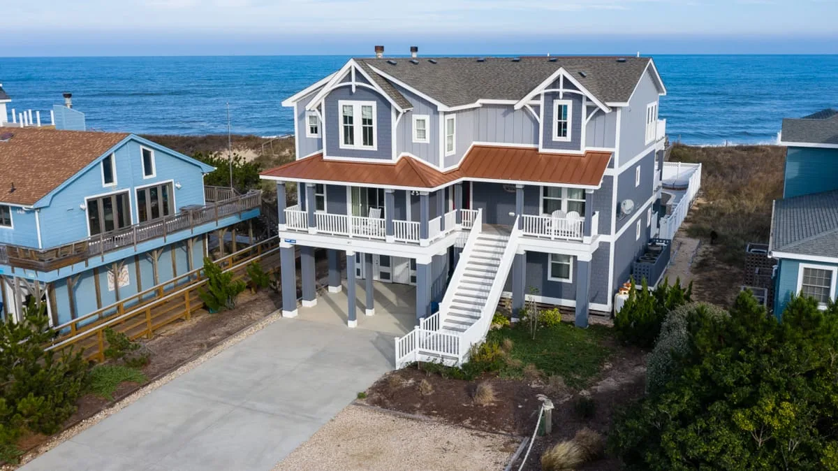 Una casa costera con terraza elevada y escalera exterior mira hacia el océano.