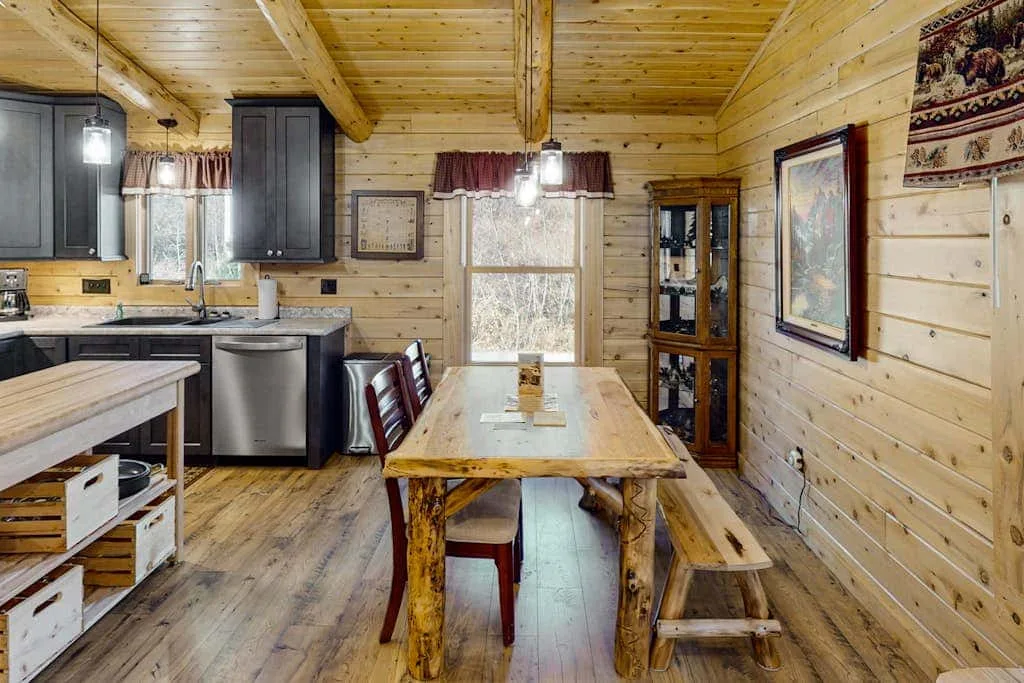 Comedor con paredes de madera y una mesa junto a una cocina compacta.