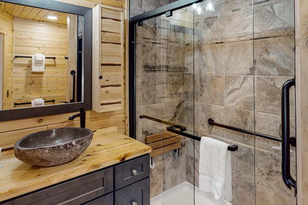 Un baño con un lavabo de recipiente junto a una ducha con mampara de vidrio.
