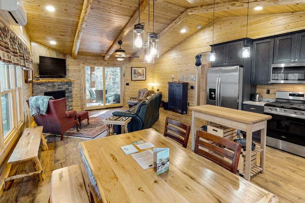A wood-paneled open-plan living and dining area with a kitchen and dining table.