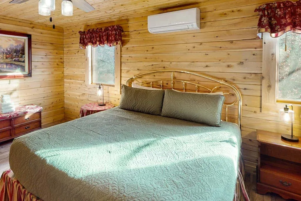 Un dormitorio con una cama grande, mesitas de noche y ventanas.