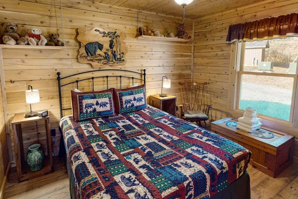 Un dormitorio con una colcha estampada, mesitas de noche y una ventana grande.