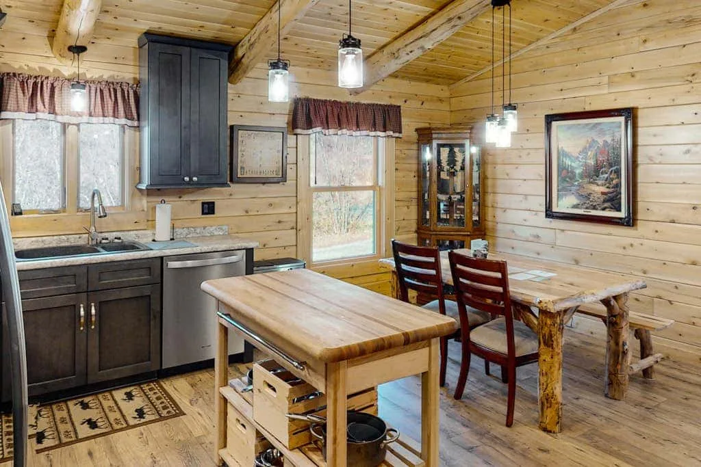 Cocina y comedor revestidos de madera, con una isla central y una mesa de comedor.