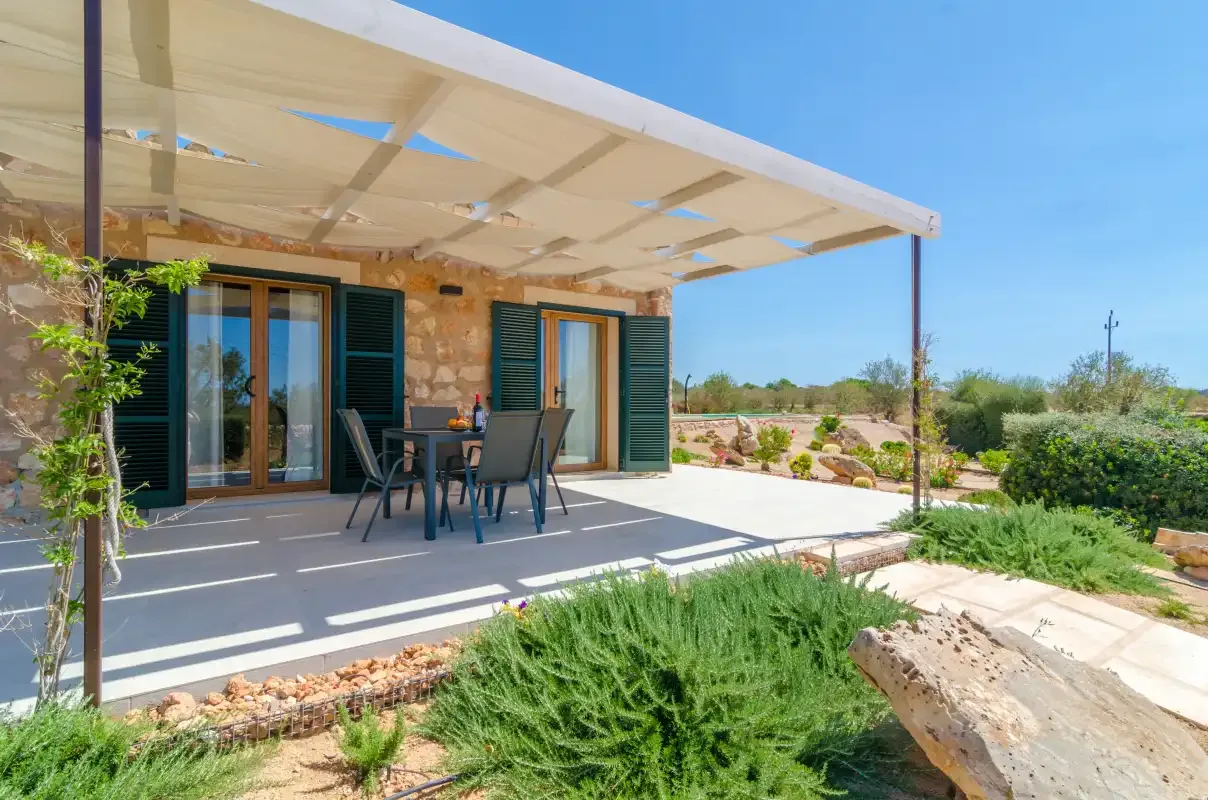 Un patio a la sombra con asientos al aire libre junto a un muro de piedra.