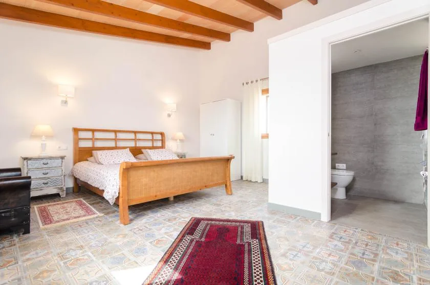 Un dormitorio con una cama de madera y una puerta abierta al baño.