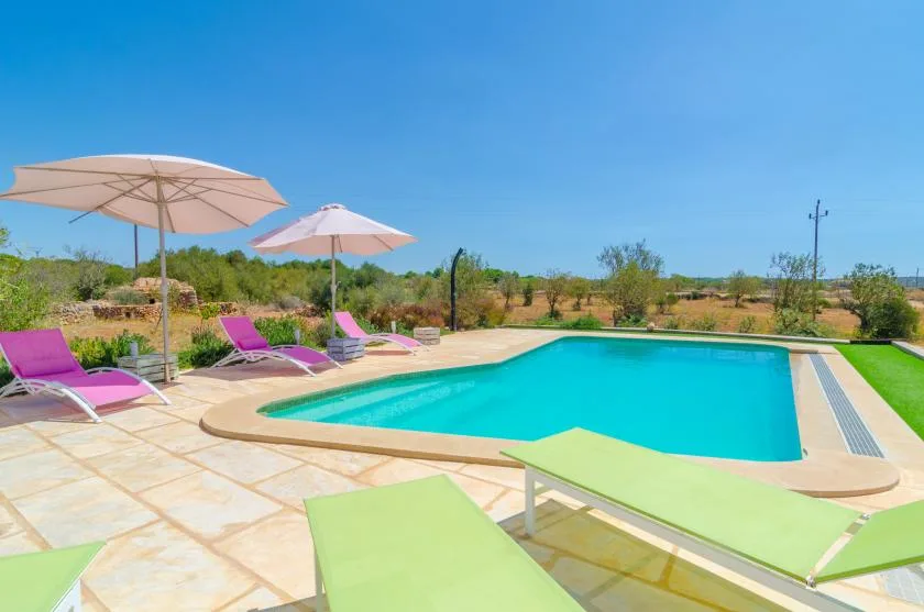 Una piscina al aire libre está rodeada de asientos reclinables y sombrillas.