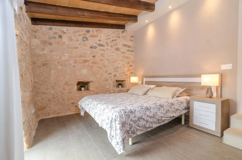 Un dormitorio con una cama grande junto a una pared de piedra y vigas de madera.