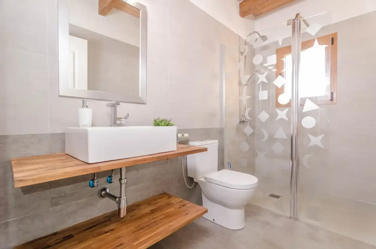 Un baño luminoso con lavabo, inodoro y ducha de cristal.