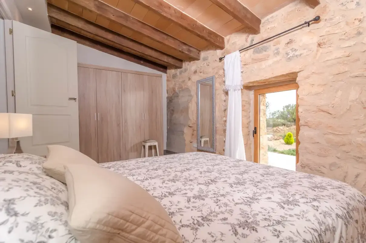 Un dormitorio con una cama, armarios de madera y una puerta abierta.
