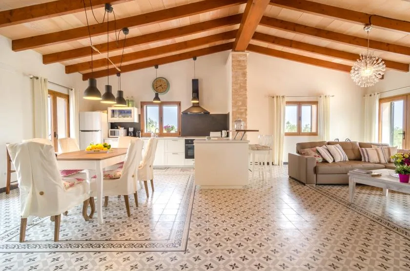 Una luminosa sala-comedor de concepto abierto con cocina y vigas de madera a la vista.