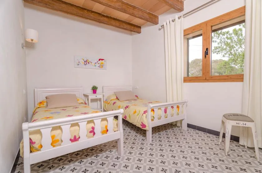 Un dormitorio con dos camas individuales, ropa de cama estampada y una ventana con marco de madera.